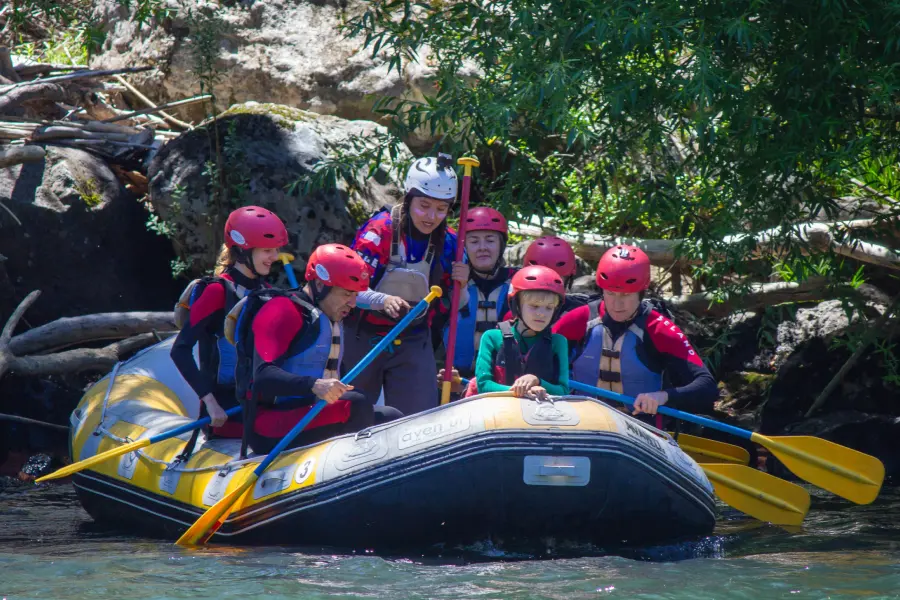 “Participantes viviendo la emoción del rafting río Trancura bajo en aguas cristalinas.”