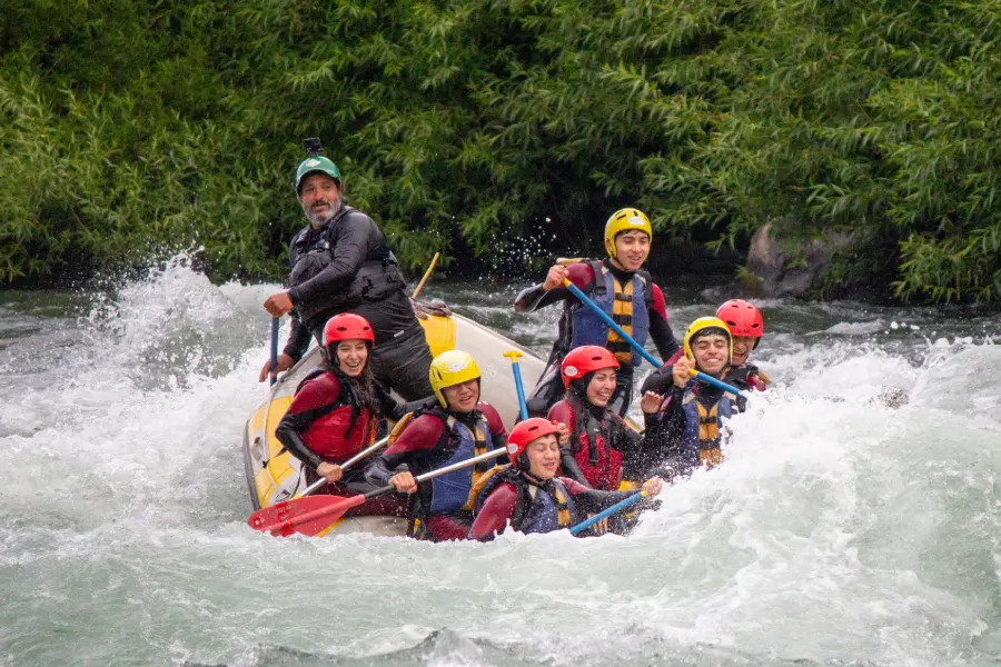 “Grupo remando en los rápidos del rafting río Trancura bajo con guías profesionales.”