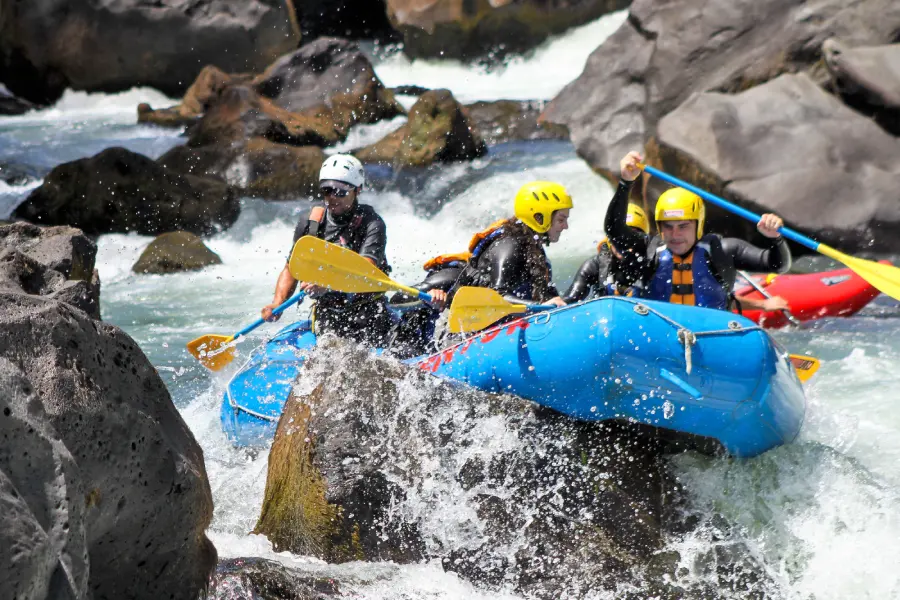 “Equipo de turistas remando juntos en los rápidos del rafting río Trancura alto.”