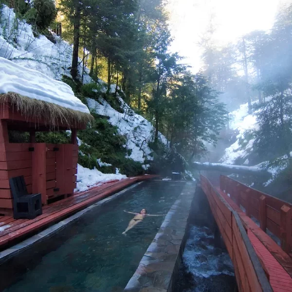 “Turista disfrutando termas rodeadas de nieve en Termas Geométricas Invernal.”