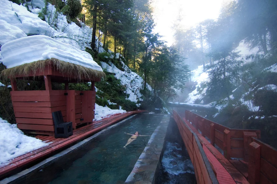 “Turista disfrutando termas rodeadas de nieve en Termas Geométricas Invernal.”