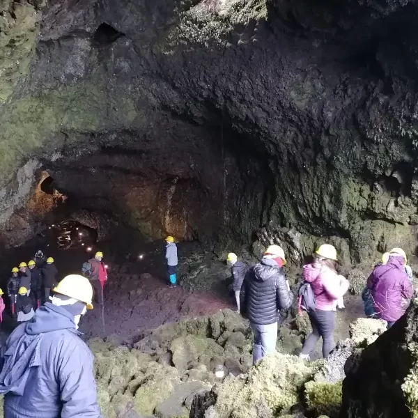 “Visitantes recorriendo una cueva en el Tour Invernal a las Cuevas Volcánicas.”