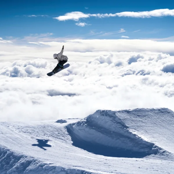 “Turista realizando saltos con equipos de alquiler de ski o snowboard.”